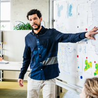 Man gesturing in front of a large map.